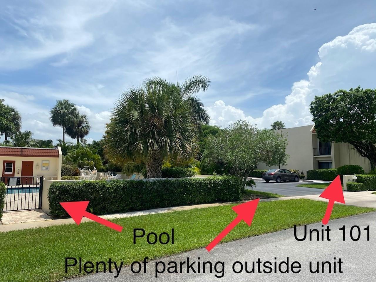 An exterior view of a residential building with a swimming pool and adjacent parking area — 1714 Consulate Place # 101, West Palm Beach FL 33401, WEST PALM BEACH, FL