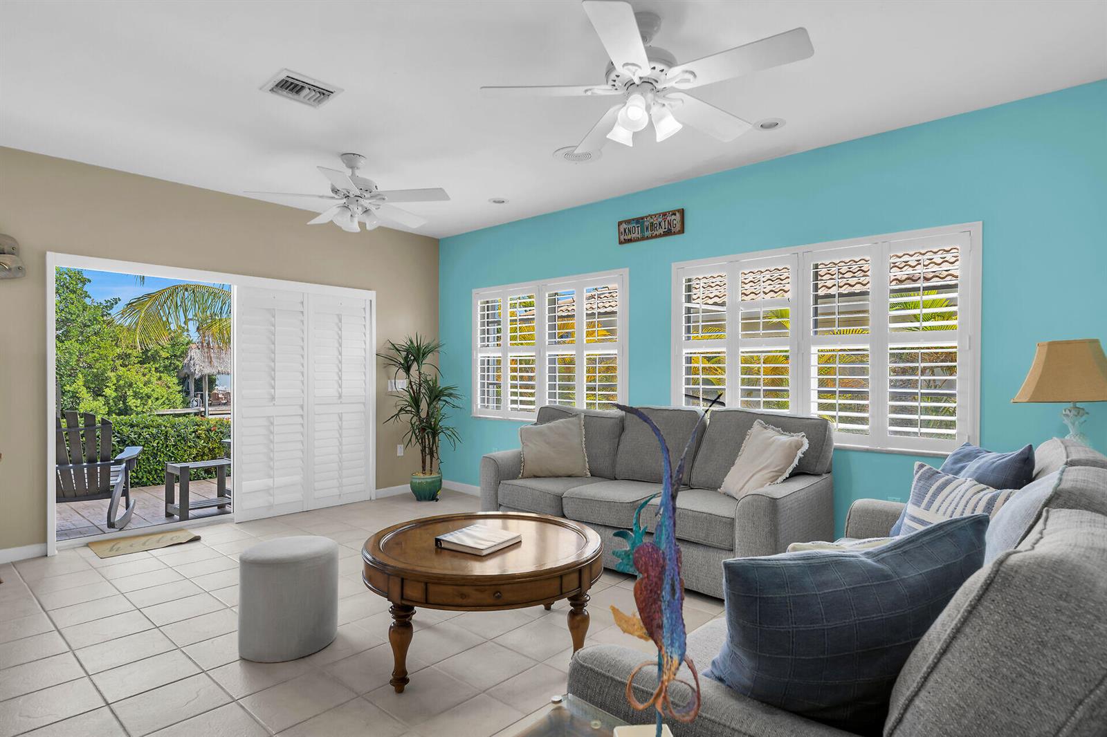 A living room with light blue and tan walls, tile flooring, and sliding glass doors — 180 9th Street, FL 33051, FL
