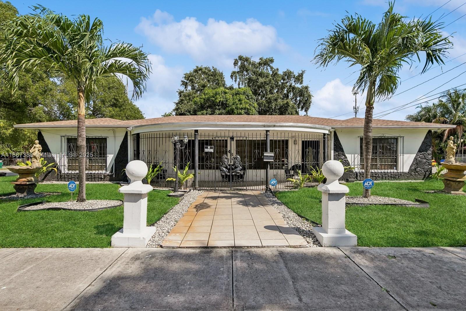 A single-story house features a gated front patio, two palm trees, and lawn statues — 469 NW 69th St, Miami FL 33150, MIAMI, FL