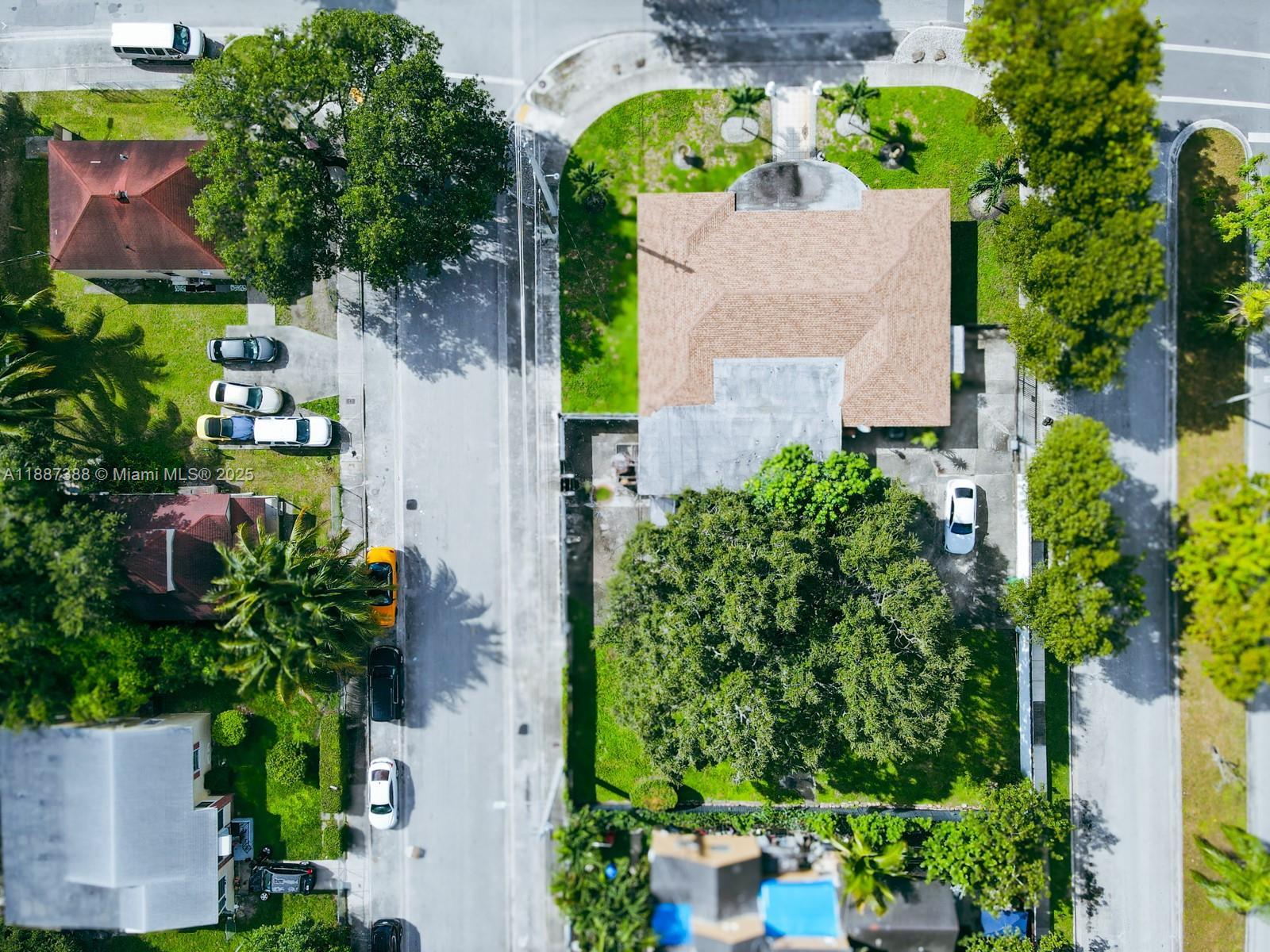 An aerial view shows a residential property with a tan roof, trees, and parked cars — 469 NW 69th St, Miami FL 33150, MIAMI, FL
