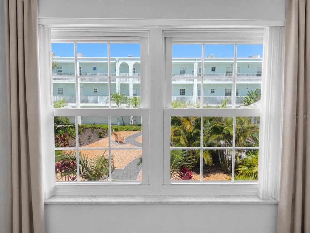 A double-hung window with white frames overlooks a courtyard and a multi-story building — 1706 BELLEAIR FOREST DRIVE UNIT 244, BELLEAIR, FL