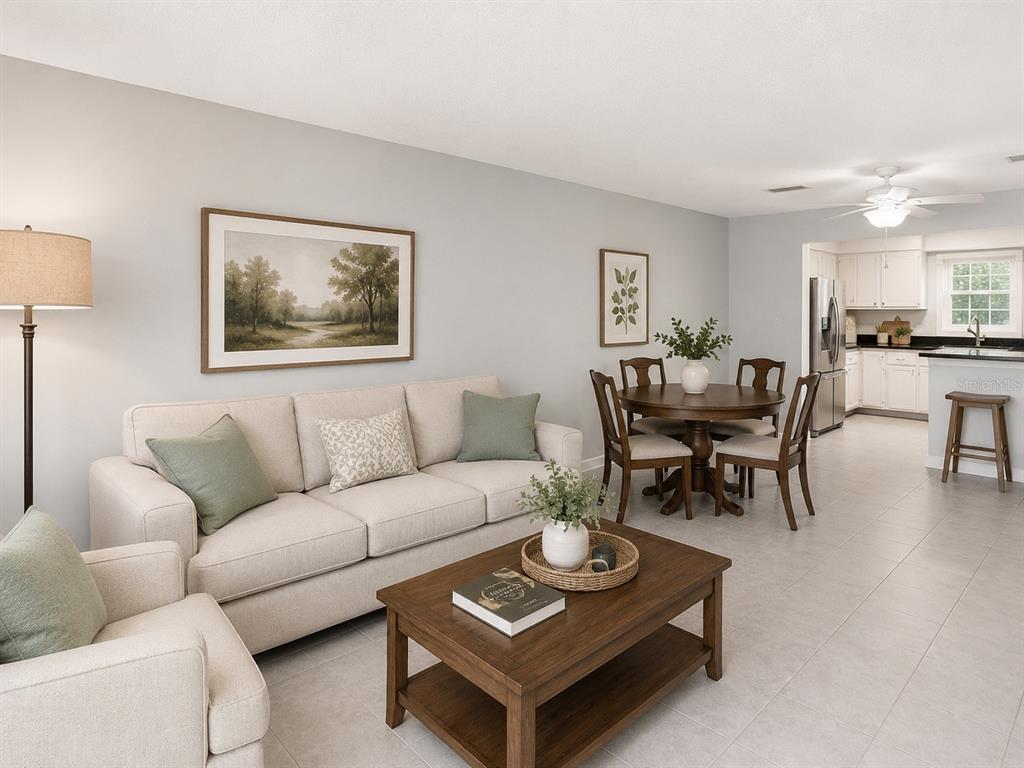 A living room with a beige sofa, coffee table, and dining area near a kitchen — 1706 BELLEAIR FOREST DRIVE UNIT 244, BELLEAIR, FL