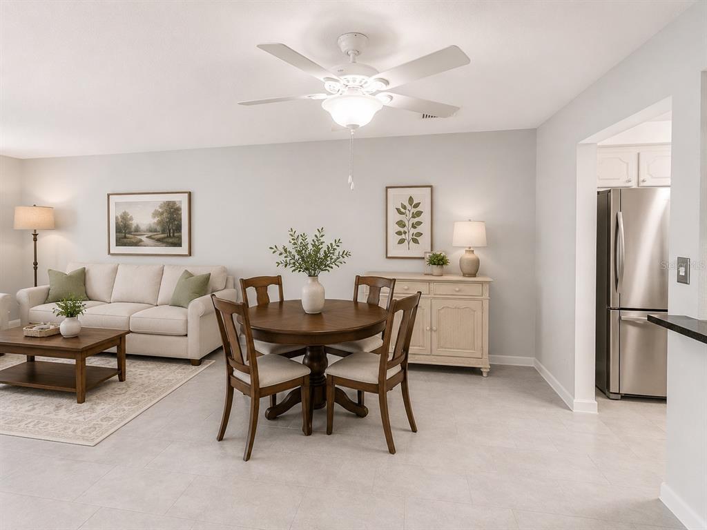 A dining area with a round wooden table sits adjacent to a living room — 1706 BELLEAIR FOREST DRIVE UNIT 244, BELLEAIR, FL