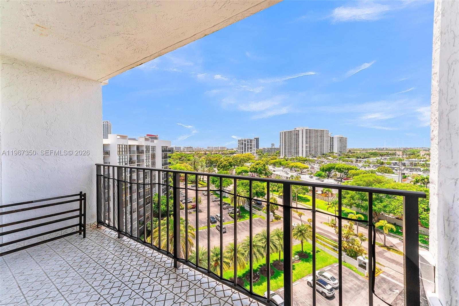 An empty living area features light blue walls, beige tile flooring, and a mirrored wall — 800 Parkview Dr # 1007, Hallandale Beach FL 33009, HALLANDALE BEACH, FL