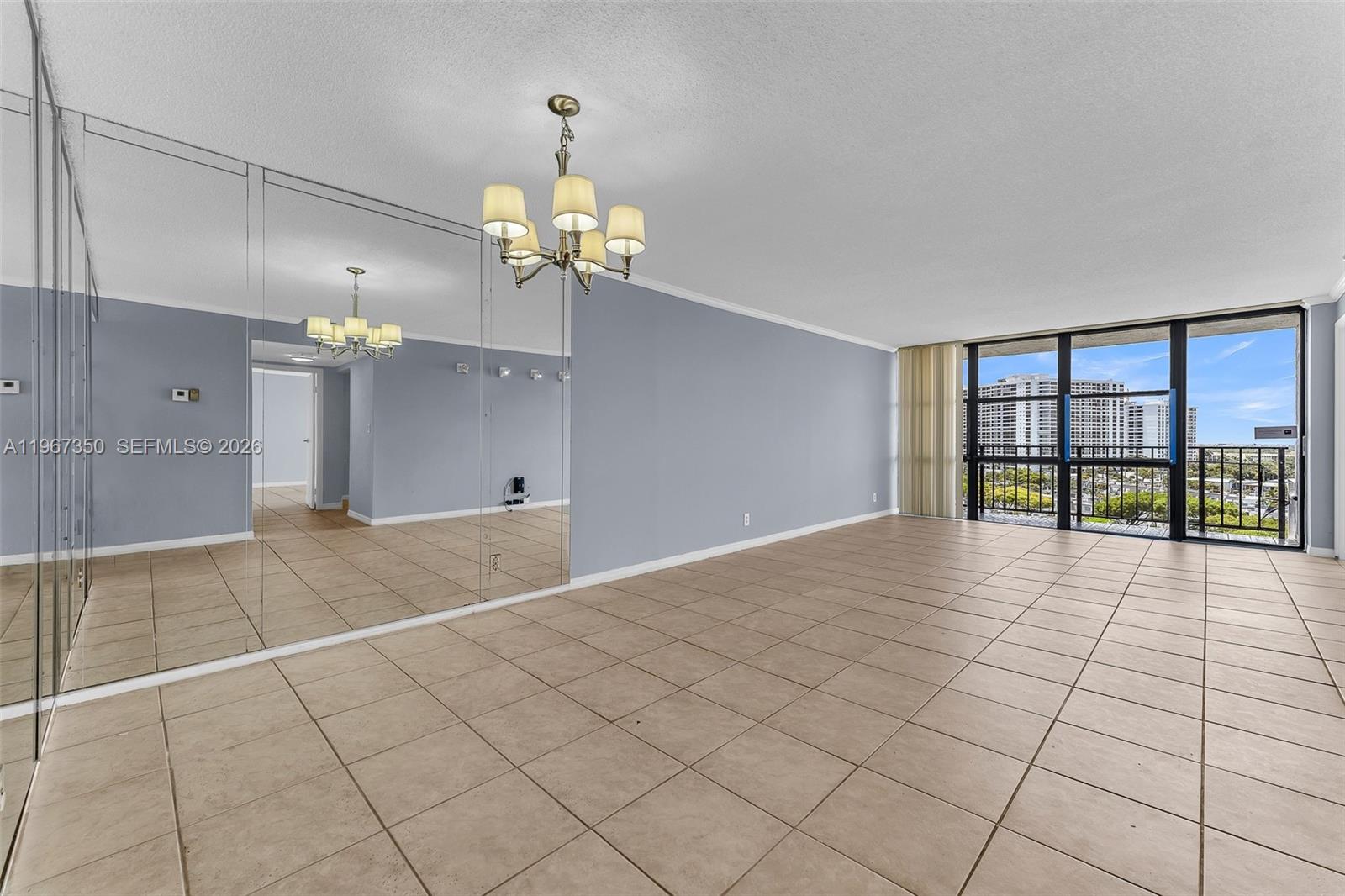 An empty room features light blue walls, beige tile flooring, and a large window view — 800 Parkview Dr # 1007, Hallandale Beach FL 33009, HALLANDALE BEACH, FL