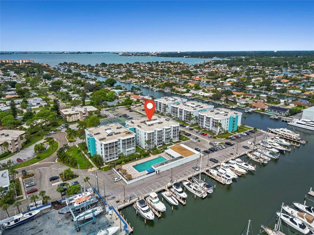 An aerial view shows a multi-story apartment complex with a pool and boat slips — 4908 38TH WAY S UNIT 501, ST PETERSBURG, FL
