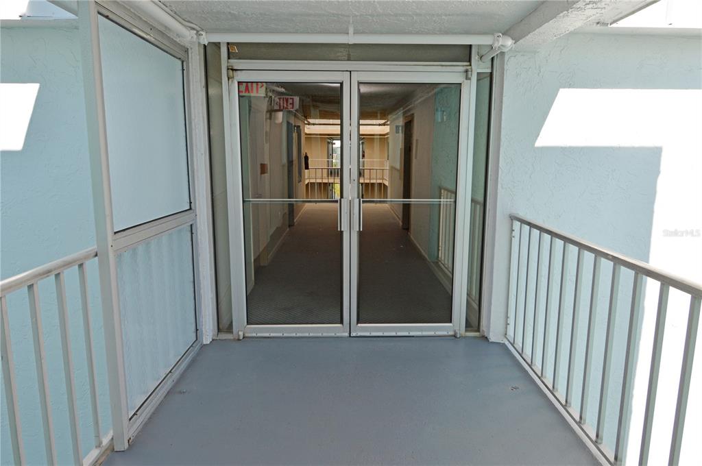 A view of a covered outdoor walkway leading to a set of glass double doors — 4908 38TH WAY S UNIT 501, ST PETERSBURG, FL