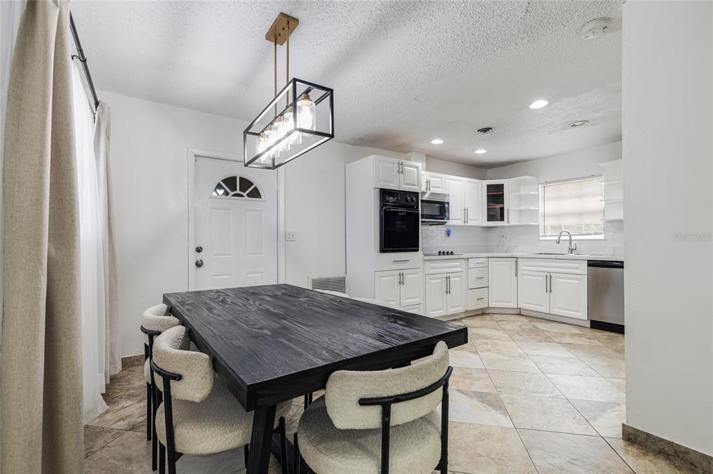 A kitchen and dining area with white cabinets, a black table, and tile flooring — 24 NW 42ND TERRACE, PLANTATION, FL