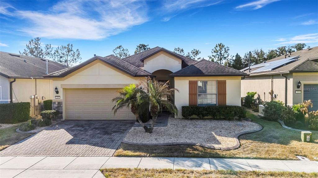A single-story house exterior with a gravel front yard, a palm tree, and a driveway — 329 ALICANTE COURT, DAVENPORT, FL