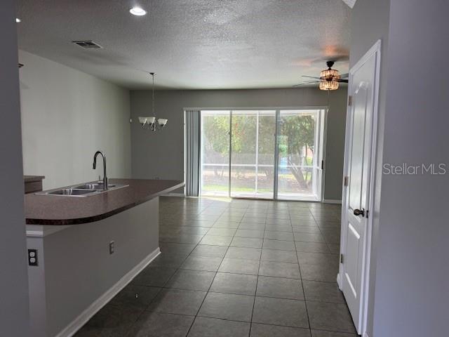 A kitchen island with a sink faces an open living area with tile flooring — 302 MAYBECK COURT, SANFORD, FL