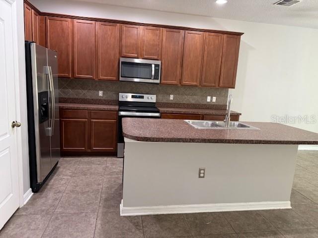 A kitchen features wood cabinets, stainless steel appliances, and a central island with a sink — 302 MAYBECK COURT, SANFORD, FL