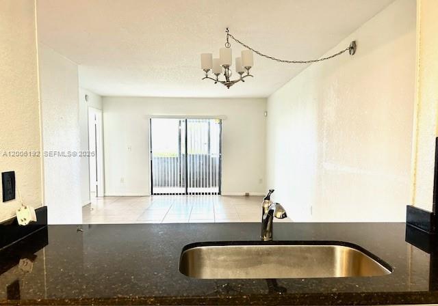 A kitchen sink and dark countertop overlook an open living area with a sliding door — 871 NE 207th Ter # 101, Miami FL 33179, MIAMI, FL