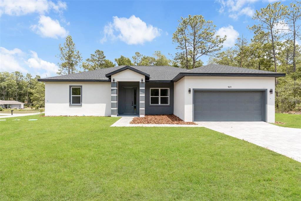 A single-story house with a white stucco exterior, gray trim, and a two-car garage — 9651 W PINEVIEW WAY, DUNNELLON, FL