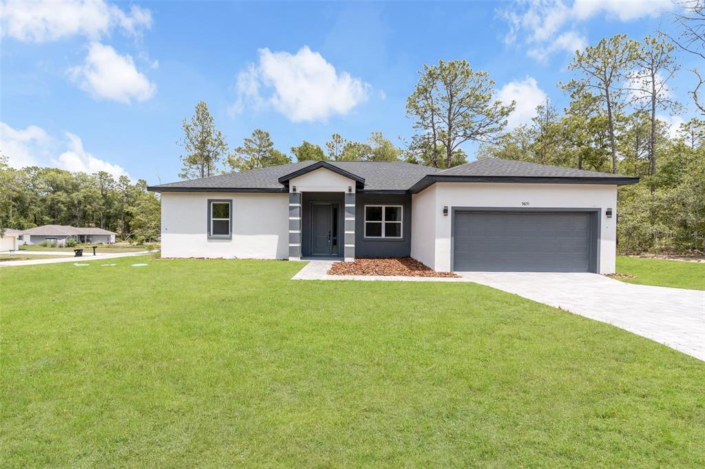 A single-story house with a white stucco exterior, dark gray garage, and a front entryway — 9651 W PINEVIEW WAY, DUNNELLON, FL