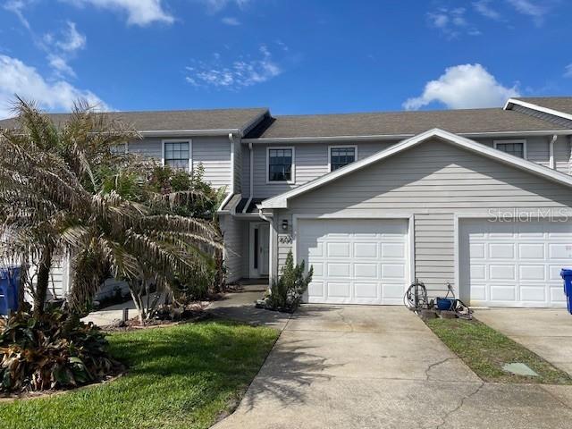 A two-story townhouse with light gray siding, two garage doors, and a palm tree — 606 ORANGE BLOSSOM DRIVE, WINTER HAVEN, FL