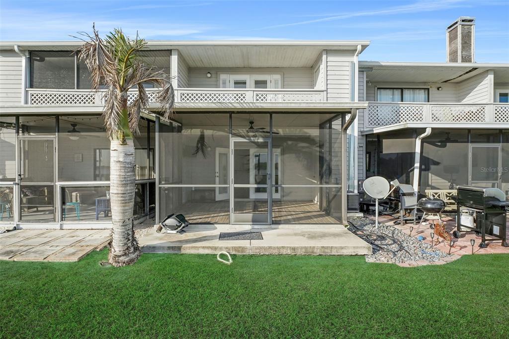 A two-story townhouse exterior features a screened-in ground floor patio and an upper-level balcony — 606 ORANGE BLOSSOM DRIVE, WINTER HAVEN, FL