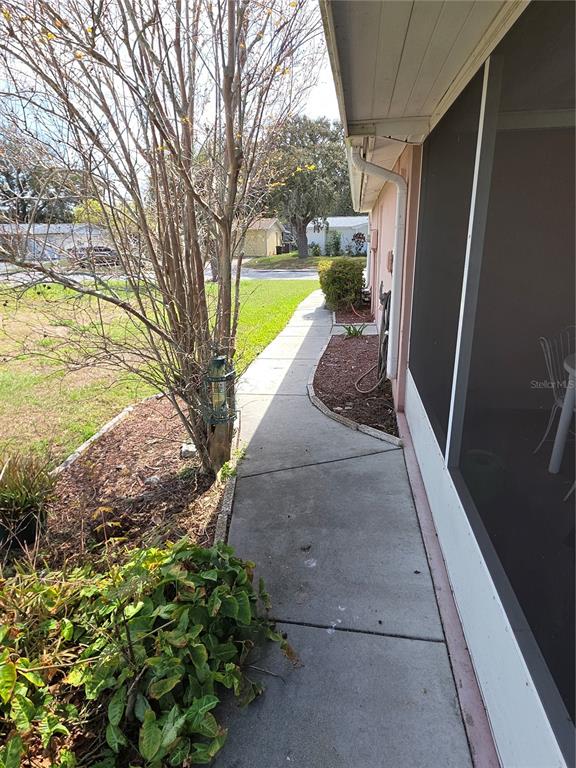A concrete walkway runs along the side of a house next to a screened porch — 7207 ASHWOOD DRIVE, PORT RICHEY, FL