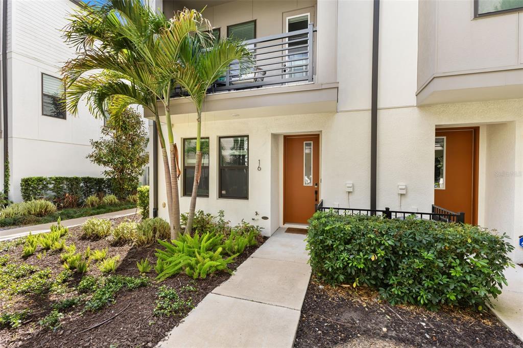 A modern townhouse exterior features a brown front door, a small balcony, and landscaping — 2511 N GRADY AVENUE UNIT 16, TAMPA, FL