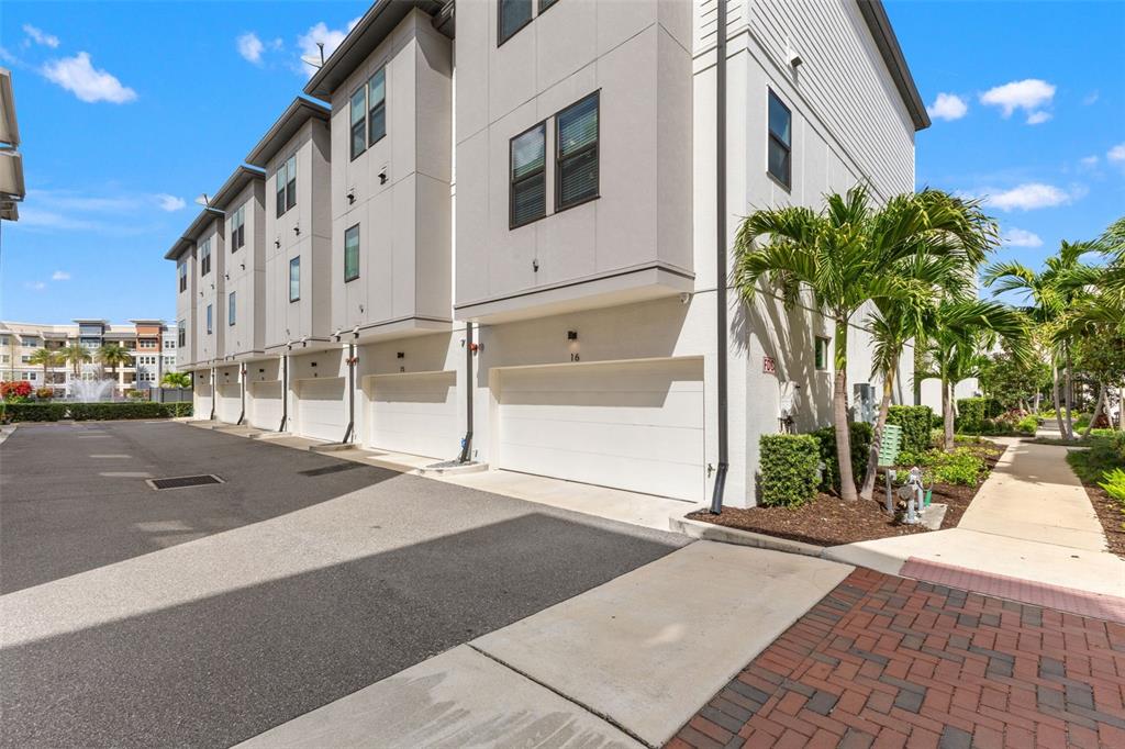 A row of modern townhouses with white garage doors and palm trees under a blue sky — 2511 N GRADY AVENUE UNIT 16, TAMPA, FL