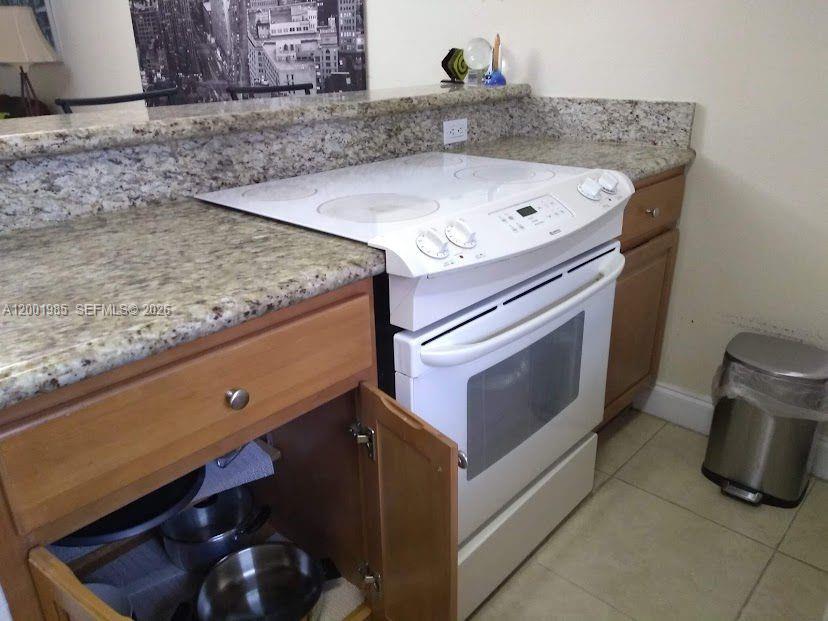 A kitchen features a white electric range, granite countertops, and light wood cabinetry — 7530 SW 82nd St # G102, Miami FL 33143, MIAMI, FL
