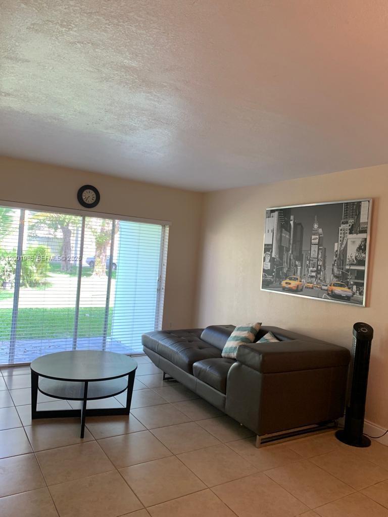 A living room features a dark leather sofa, a round coffee table, and tile flooring — 7530 SW 82nd St # G102, Miami FL 33143, MIAMI, FL