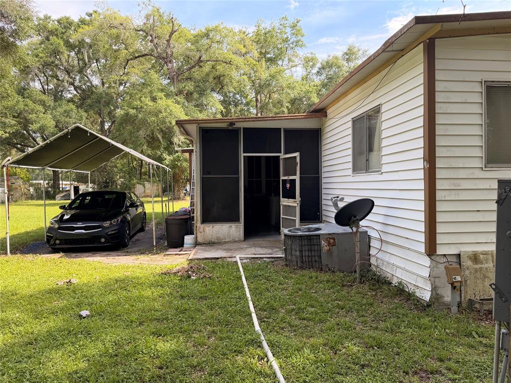 A white house with a screened-in porch, a car under a carport, and a satellite dish — 201 NW 136TH TERRACE, OCALA, FL