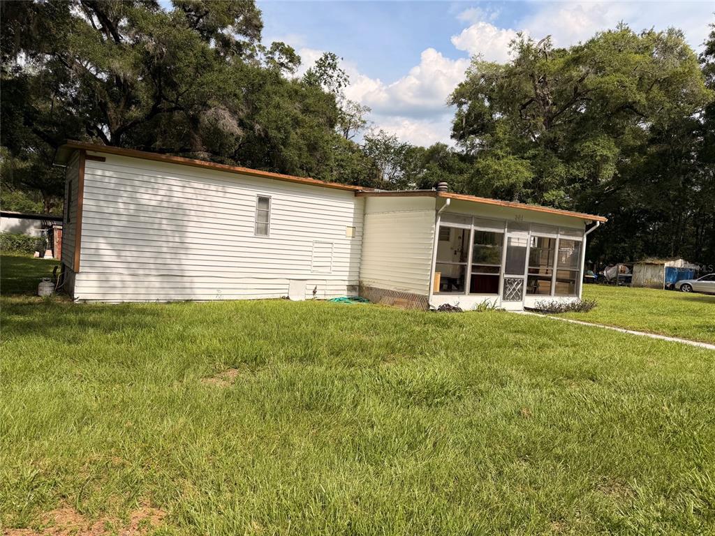 A white mobile home with a screened-in porch sits on a grassy lot — 201 NW 136TH TERRACE, OCALA, FL