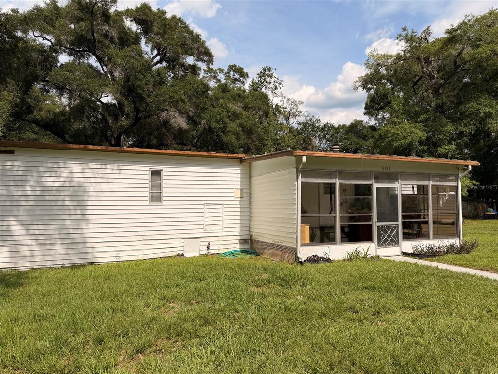 A white house with horizontal siding and a screened-in porch sits on a grassy lawn — 201 NW 136TH TERRACE, OCALA, FL
