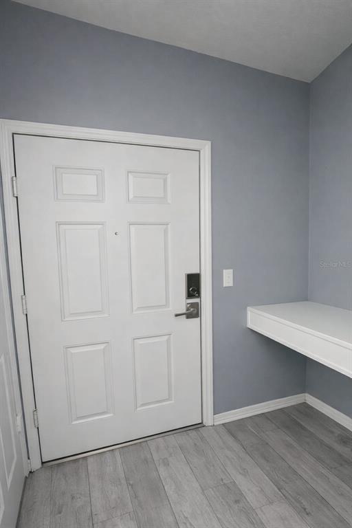 A white door with a smart lock stands next to a floating shelf in a room — 3016 BONFIRE BEACH DRIVE UNIT 104, KISSIMMEE, FL