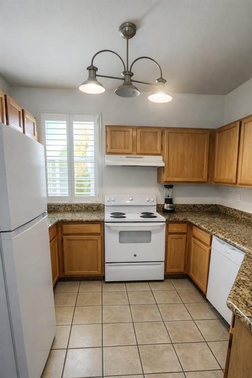 A kitchen features light wood cabinets, granite countertops, a white stove, and a tile floor — 3016 BONFIRE BEACH DRIVE UNIT 104, KISSIMMEE, FL