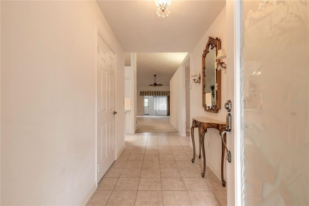 A tiled entryway leads to a hallway with a console table, mirror, and distant living area — 2626 TURNBULL ESTATES DRIVE, NEW SMYRNA BEACH, FL