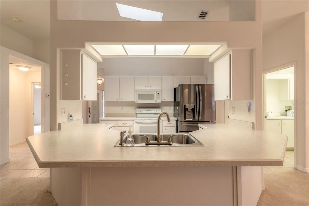 A kitchen with white cabinets, stainless steel appliances, and a peninsula countertop with a sink — 2626 TURNBULL ESTATES DRIVE, NEW SMYRNA BEACH, FL