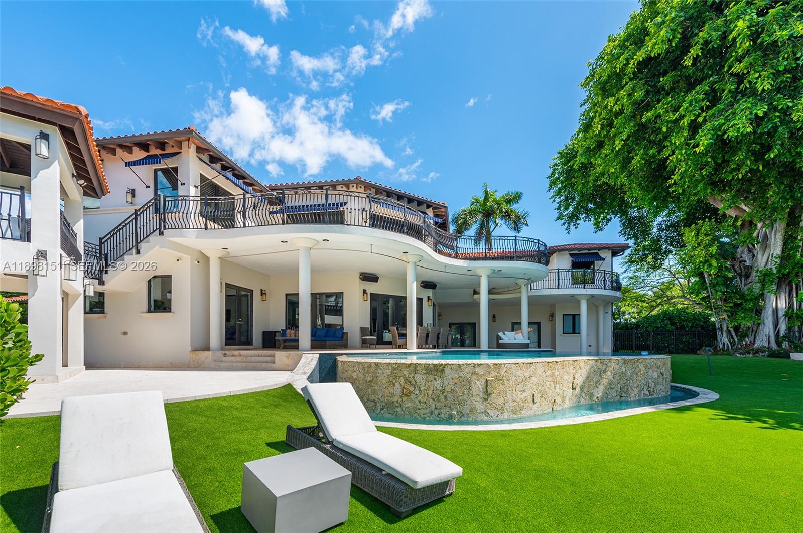 A multi-story house with a curved balcony, swimming pool, and lounge chairs on a lawn — 6700 Granada Blvd, Coral Gables FL 33146, CORAL GABLES, FL