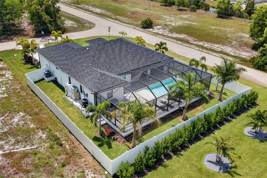 An aerial view shows a house with a screened-in pool and a white vinyl fence — 4700 NW 38TH AVENUE, CAPE CORAL, FL