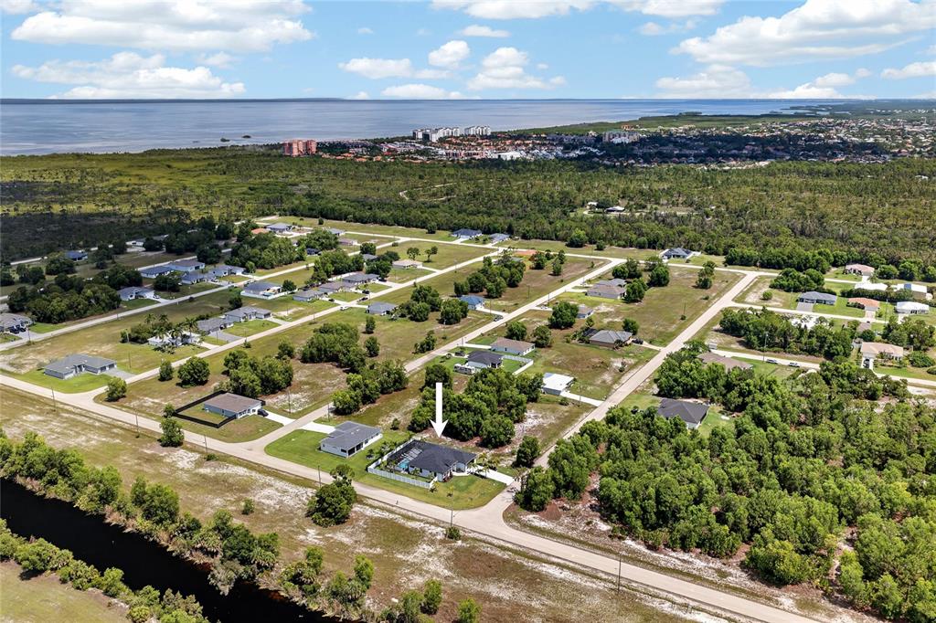 An aerial view shows a residential neighborhood with a marked house near a canal — 4700 NW 38TH AVENUE, CAPE CORAL, FL