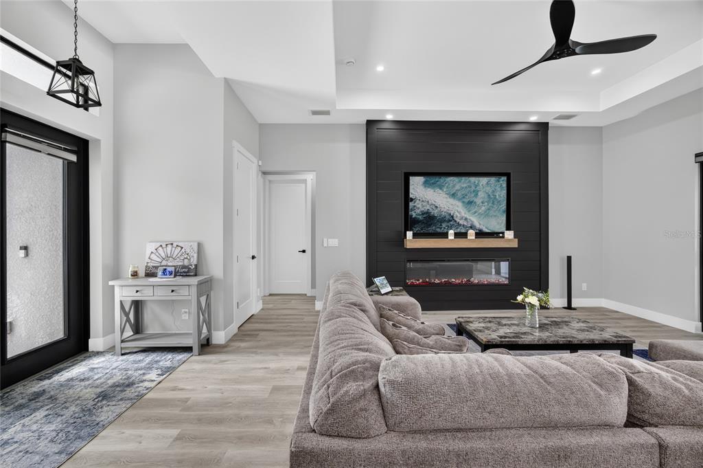 A living room features a black shiplap accent wall with a fireplace and a sectional sofa — 4700 NW 38TH AVENUE, CAPE CORAL, FL