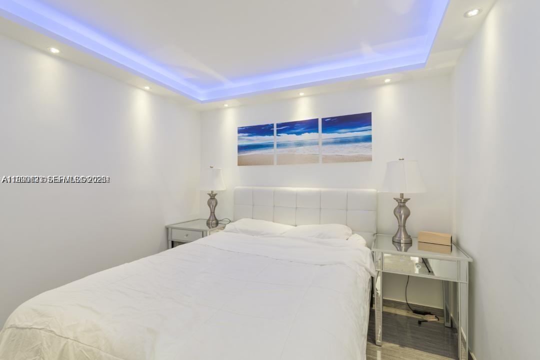 A bedroom features a white bed, mirrored nightstands, and a blue-lit tray ceiling — 401 Ocean Dr # 1124, Miami Beach FL 33139, MIAMI BEACH, FL