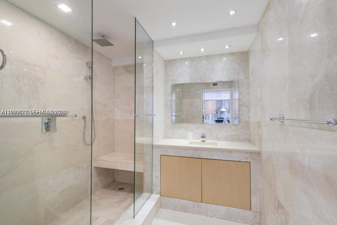 A bathroom features a glass-enclosed walk-in shower with a bench and a marble vanity — 401 Ocean Dr # 1124, Miami Beach FL 33139, MIAMI BEACH, FL