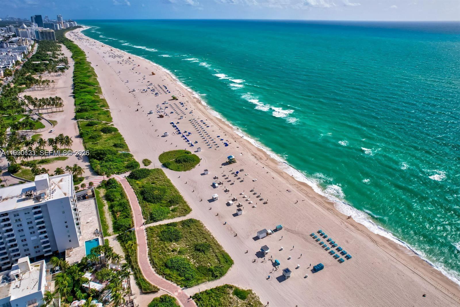 An aerial view shows a sandy beach, turquoise ocean, and a coastal building with a pool — 401 Ocean Dr # 1124, Miami Beach FL 33139, MIAMI BEACH, FL