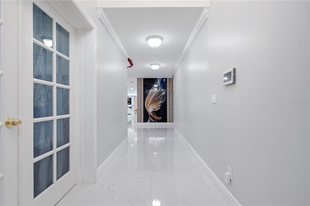 A bright hallway features white marble-look tile floors, recessed lighting, and a large abstract artwork — 16839 WHIRLEY ROAD, LUTZ, FL