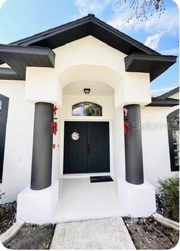 The exterior of a house features a covered entryway with two dark columns and double doors — 14 WAYLAND PLACE, PALM COAST, FL
