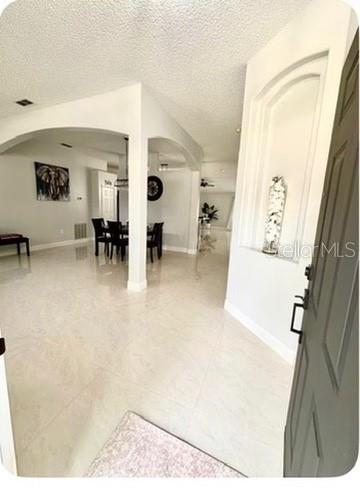 A view from an entryway into a dining area with tiled floors and arched openings — 14 WAYLAND PLACE, PALM COAST, FL