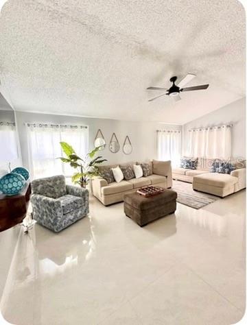 A living room features a beige sofa, a patterned armchair, and a brown ottoman on tile — 14 WAYLAND PLACE, PALM COAST, FL