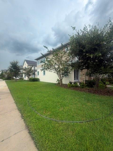 A two-story house with light-colored siding and stone accents sits behind a green lawn — 8001 NEMOURS PARKWAY, ORLANDO, FL