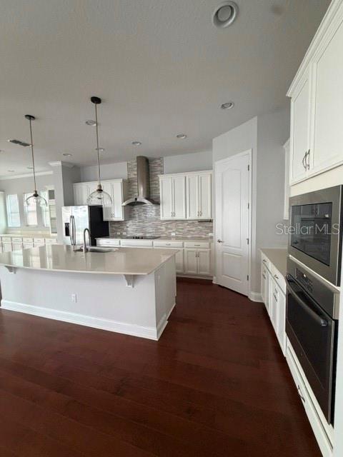 A kitchen features white cabinets, a large island with pendant lights, and dark hardwood floors — 8001 NEMOURS PARKWAY, ORLANDO, FL