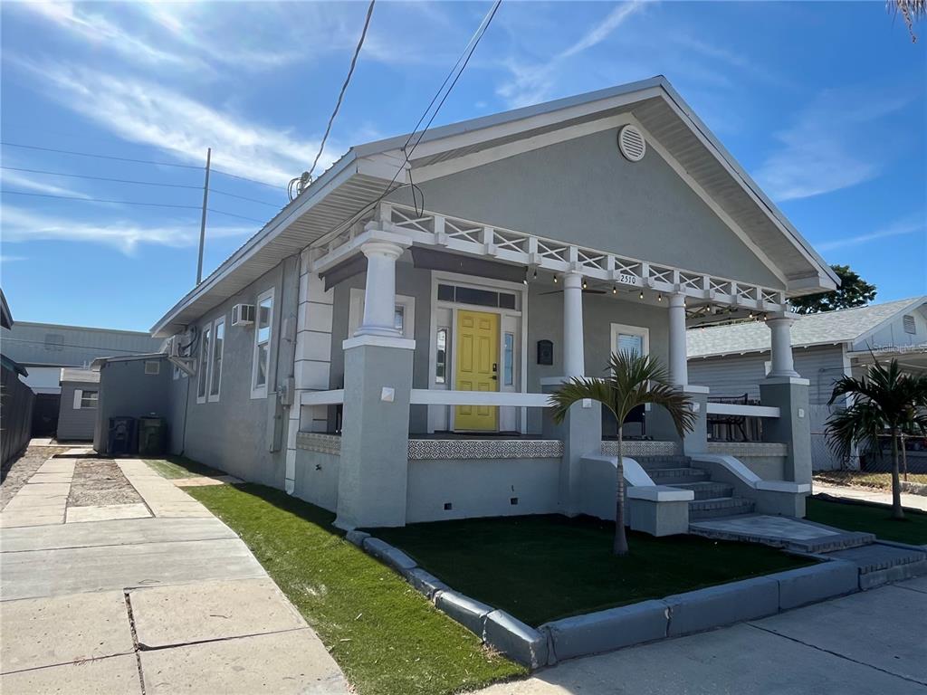 A gray bungalow with a yellow front door and a covered porch with white columns — 2510 W MAIN STREET, TAMPA, FL