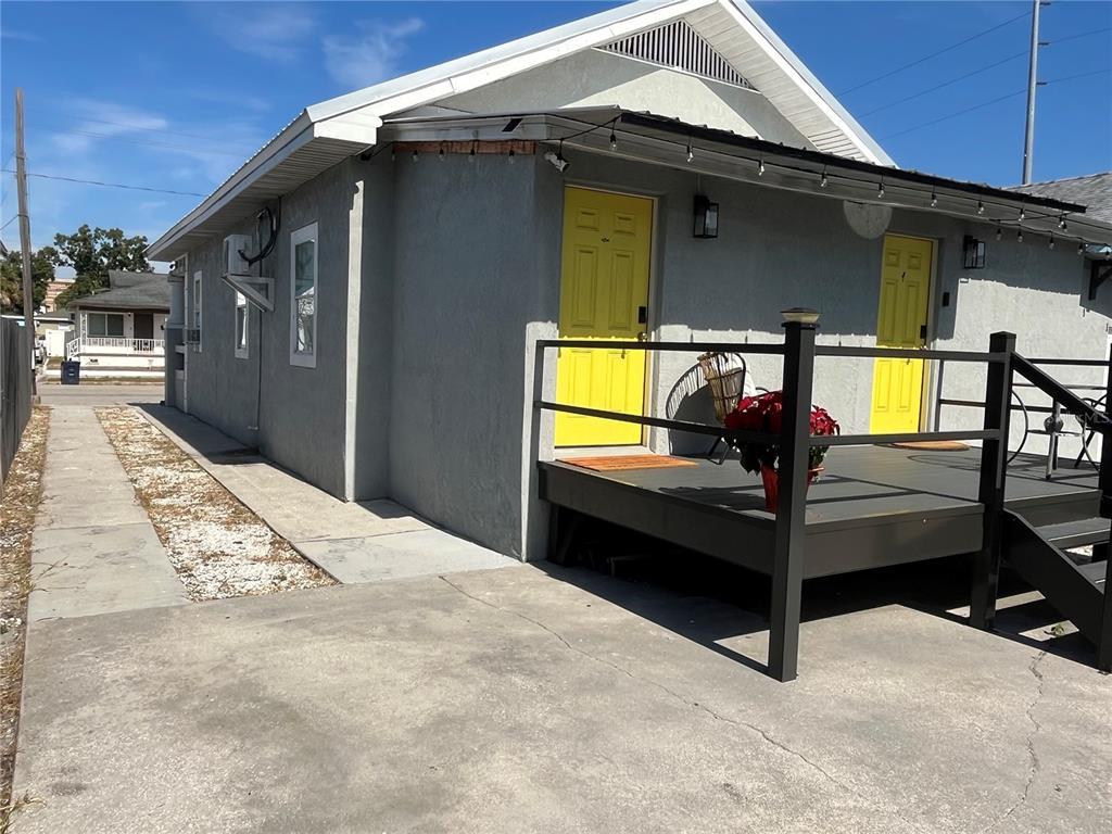 A gray stucco building features two bright yellow doors and a dark wooden front deck — 2510 W MAIN STREET, TAMPA, FL
