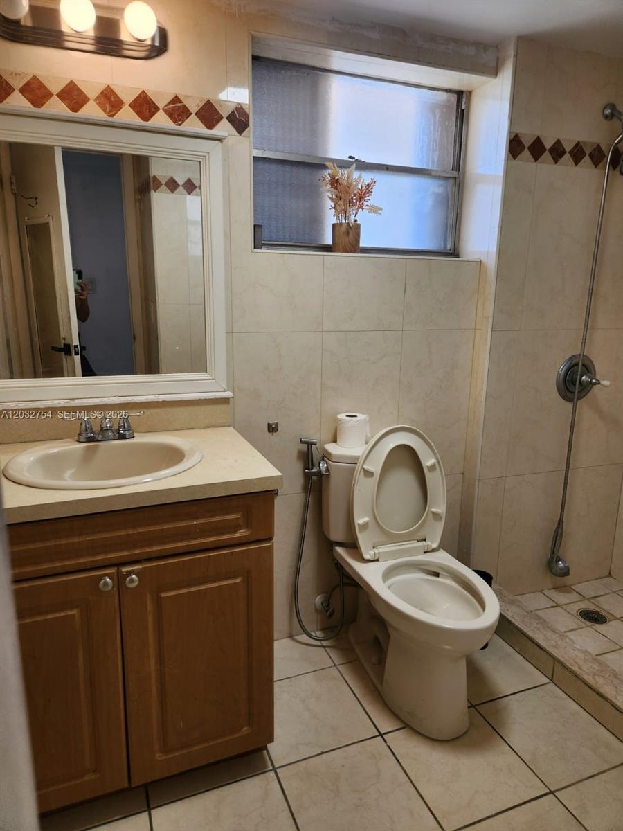 A bathroom features a wooden vanity, a toilet, and a walk-in shower with tiled walls — 160 Royal Palm Rd # 215, Hialeah Gardens FL 33016, HIALEAH GARDENS, FL