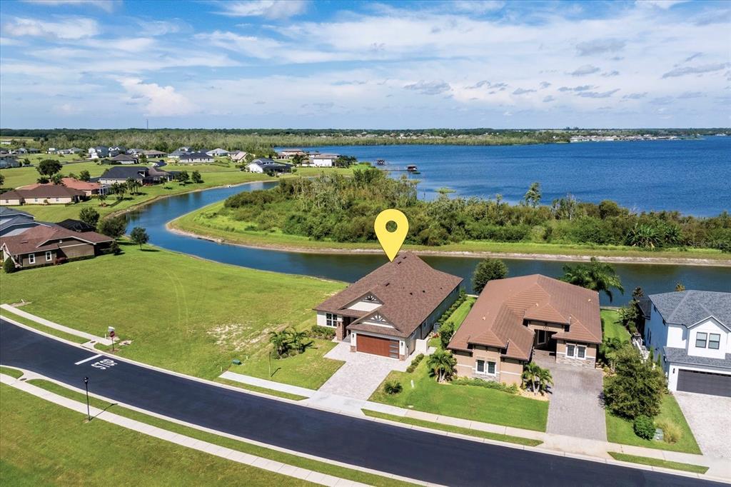An aerial view shows a suburban house with a brown roof beside a canal — 559 WATERFERN TRAIL DRIVE, AUBURNDALE, FL