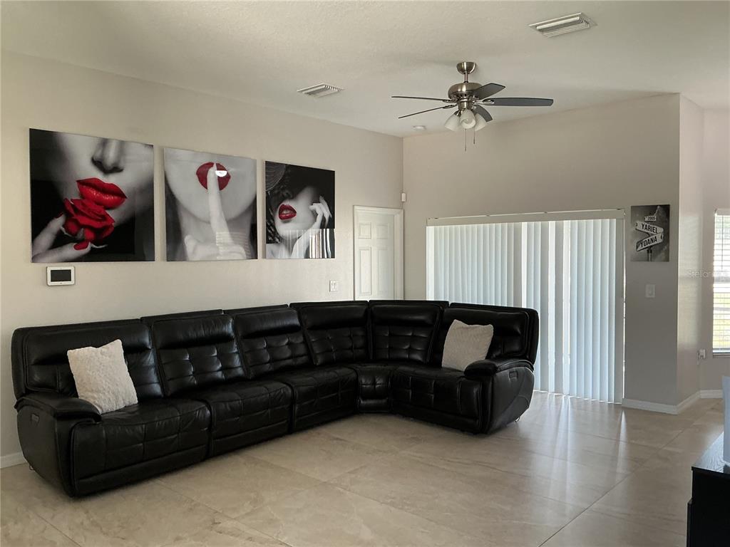 A living room features a large black sectional sofa, tiled floors, and three wall art pieces — 13262 CROWELL ROAD, BROOKSVILLE, FL